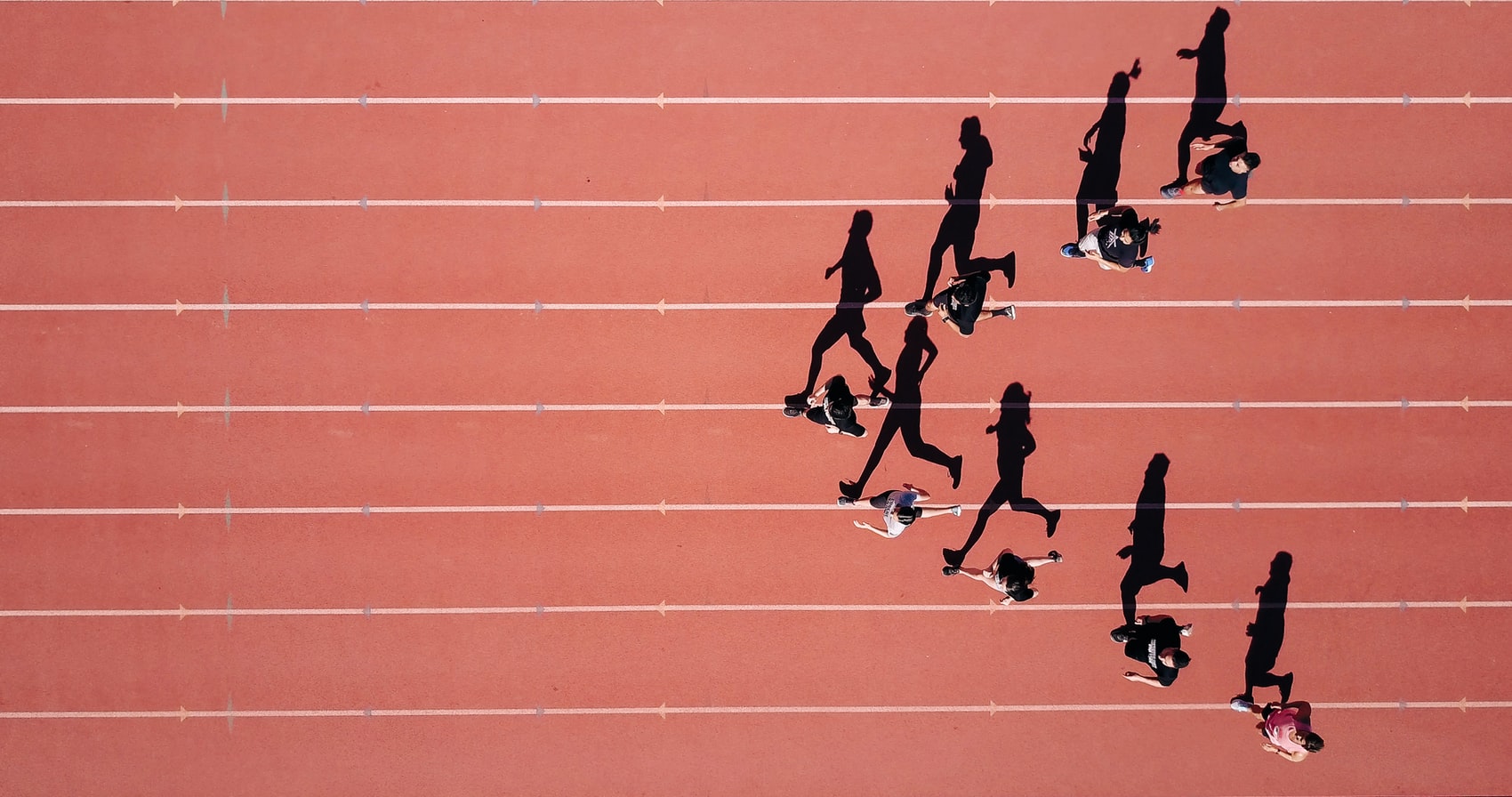 8 people running on a red running track