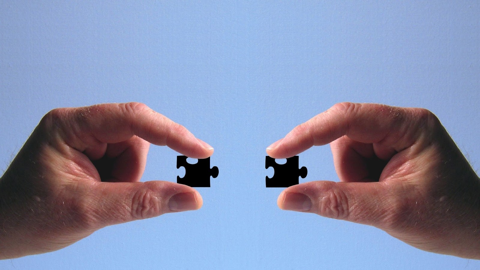 2 hands holding puzzle pieces